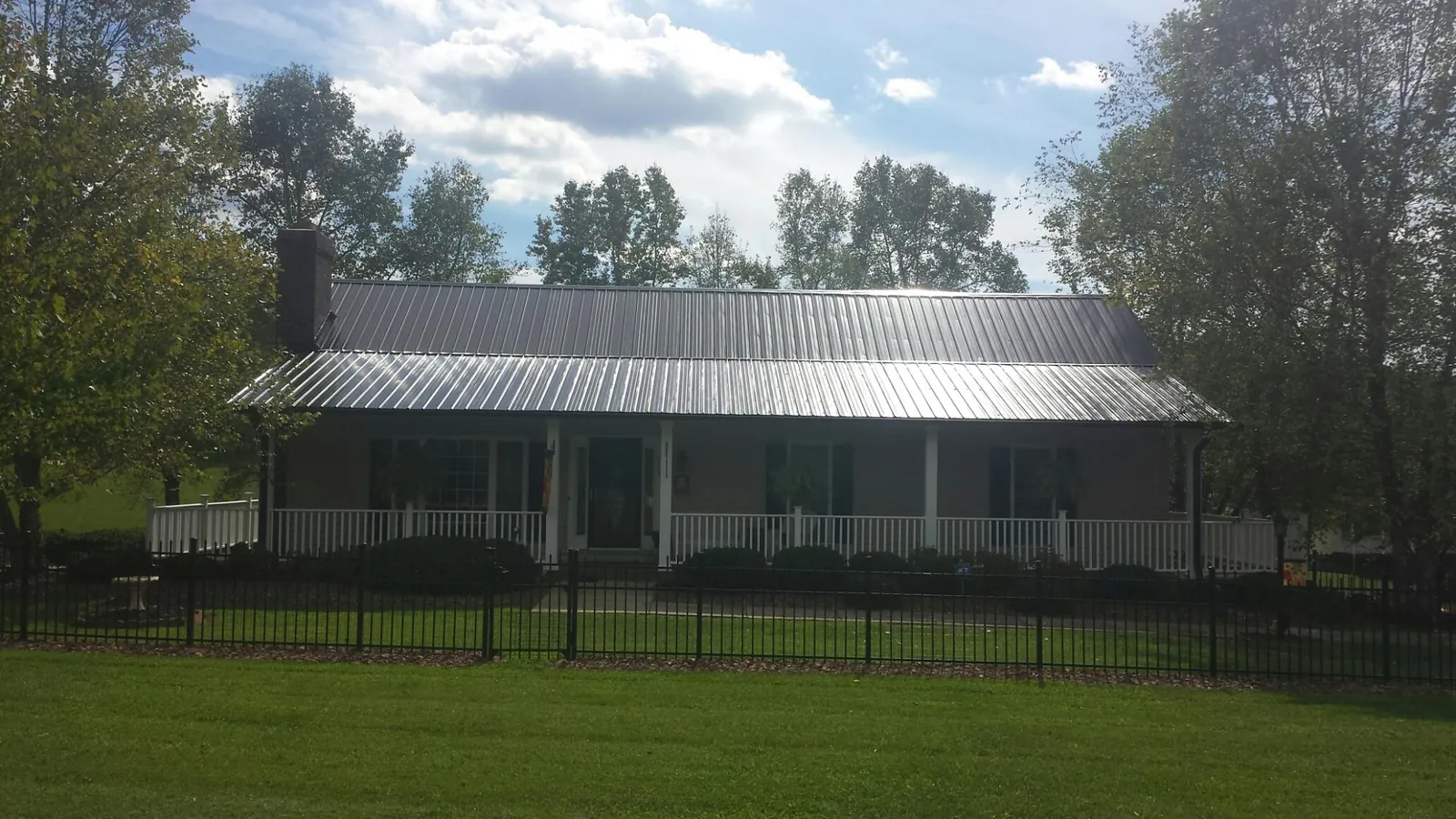 Gray metal roof on a brick ranch with a full width front porch — Gutter Guard Installation work by our crew in Elwood